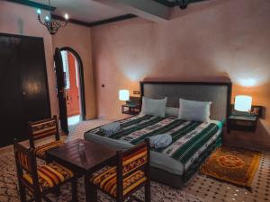 um quarto com uma cama, uma mesa e cadeiras em Hôtel LAKASBAH Ait Ben Haddou em Aït-Ben-Haddou