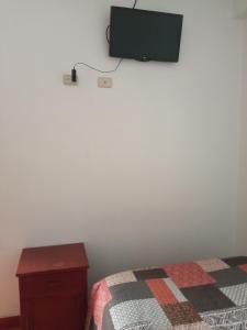 ein Schlafzimmer mit einem Bett und einem TV an der Wand in der Unterkunft HOSTAL EL CARIBE in Ayacucho