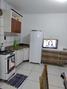 eine Küche mit einem Kühlschrank und einem TV in der Unterkunft Apartamento de hospedagem-calendula in Joinville