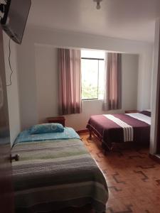 - une chambre avec 2 lits et une fenêtre dans l'établissement HOSTAL EL CARIBE, à Ayacucho