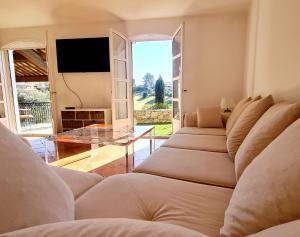 a living room with a bunch of couches and a television at SUPERBE VILLA-DOMAINE AVEC GOLF PISCINE ET TENNIS in Saint-Cyr-sur-Mer
