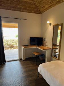 a bedroom with a bed and a desk with a television at CASA COCO II in Nianing