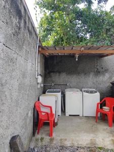 eine Terrasse mit einer Gruppe von Waschmaschinen und roten Stühlen in der Unterkunft Apartamento de hospedagem-calendula in Joinville
