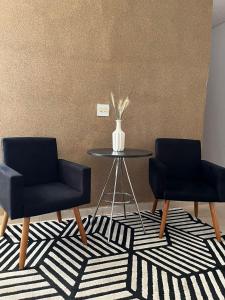 two chairs and a table in a room with a vase at HOTEL ROCHA - Olímpia in Olímpia