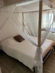 a bedroom with a canopy bed with white mosquito net at CASA COCO II in Nianing