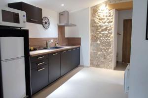 a kitchen with black cabinets and a white refrigerator at Le gîte de la vieille pierre 'climatisé' in Allex
