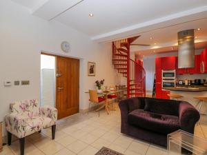 a living room with a couch and a kitchen at The Coach House in Tewkesbury