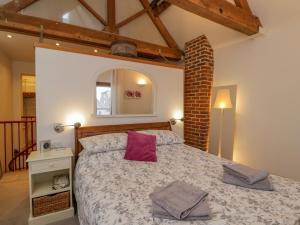 a bedroom with a large bed with a red pillow at The Coach House in Tewkesbury