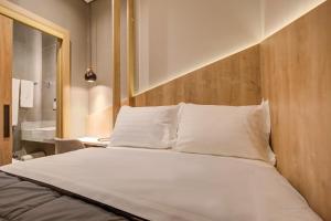 un letto con lenzuola e cuscini bianchi in una stanza di Fast Sleep Suites by Slaviero Hoteis - Hotel dentro do Aeroporto de Guarulhos - Terminal 2 - desembarque oeste a Guarulhos