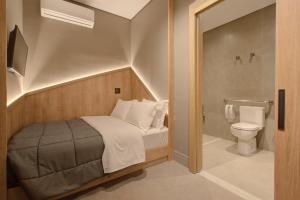 a small bedroom with a bed and a toilet at Fast Sleep Suites by Slaviero Hoteis - Hotel dentro do Aeroporto de Guarulhos - Terminal 2 - desembarque oeste in Guarulhos