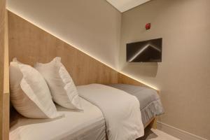 1 cama con almohadas blancas en una habitación pequeña en Fast Sleep Suites by Slaviero Hoteis - Hotel dentro do Aeroporto de Guarulhos - Terminal 2 - desembarque oeste en Guarulhos