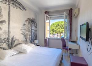 um quarto de hotel com uma cama e uma janela em Hotel Les Palmiers em Sainte-Maxime