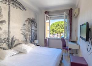 a hotel room with a bed and a window at Hotel Les Palmiers in Sainte-Maxime