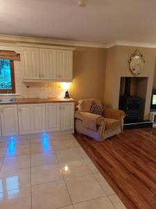 a living room with a couch and a kitchen with blue lights at Luxurious Log Cabin with lay-z spa hot tub in Ballina