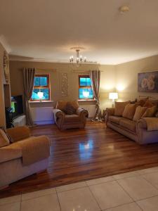 a living room with two couches and two windows at Luxurious Log Cabin with lay-z spa hot tub in Ballina