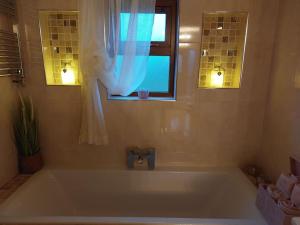 a bath tub in a bathroom with a window at Luxurious Log Cabin with lay-z spa hot tub in Ballina