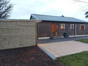 a small house with a wooden fence next to a sidewalk at Luxurious Log Cabin with lay-z spa hot tub in Ballina