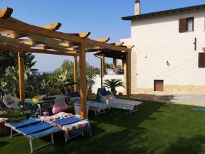 un patio con sillas, mesas y una pérgola en La Rosa Rossa, en Sciacca