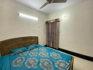 Schlafzimmer mit einem Bett mit blauer Bettwäsche und einem Deckenventilator in der Unterkunft 3 beds flat in Chittagong in Chittagong