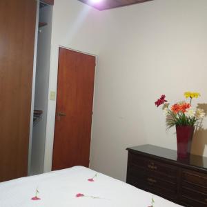 Un dormitorio con una cama y un jarrón de flores en un tocador en La casita en Paraná