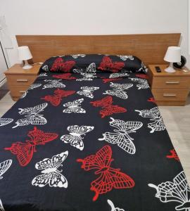 a bed with a black and white comforter with butterflies on it at PENSION ZEUS in Valladolid