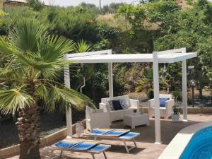 une pergola blanche avec des chaises longues et une piscine dans l'établissement villa Giò, à Racalmuto