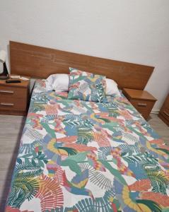ein Bett mit einer bunten Bettdecke und zwei Kissen in der Unterkunft PENSION ZEUS in Valladolid