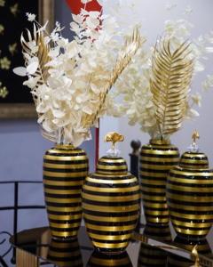 three yellow and black vases with flowers on a table at Classic House Hotel in Korçë