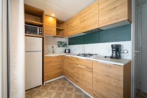 uma cozinha com armários de madeira e um frigorífico branco em Camping Les Genêts em Saint-Jean-de-Monts