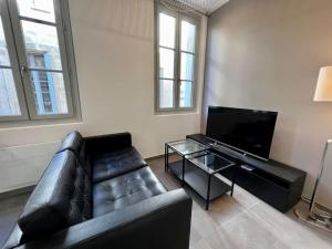 a living room with a black leather couch and a flat screen tv at Le Sainte-Ursule in Montpellier