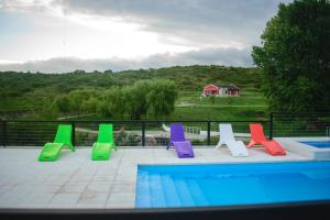 un grupo de sillas coloridas junto a una piscina en El Zuriaco en Santa Rosa de Calamuchita