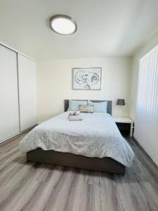 a white bedroom with a bed and a lamp at Luxury home near Disney land. Entire place! in Orange