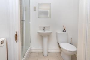 a white bathroom with a toilet and a sink at Cosy flat in leafy London in London