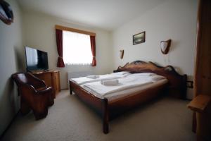 um quarto com uma cama, uma cadeira e uma televisão em Camelot Club Hotel em Vác