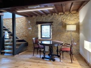 a table and chairs in a room with a stone wall at El jazmín de la Fuente casa rural in Guijo de Santa Bárbara +30 photos