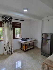 a kitchen with a table and a refrigerator at Green Lodge in Weligama