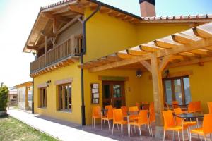 un edificio amarillo con mesas y sillas naranjas en Camping El Roble Verde, 