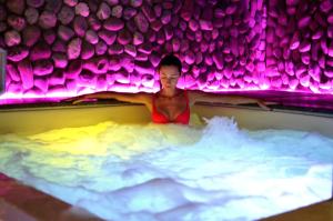 Una donna nella vasca da bagno con luci viola di Hotel Del Buono Wellness & Medical Spa a Chianciano Terme