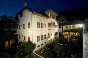 a large white building with a courtyard at night at Bosnian National Monument Muslibegovic House in Mostar