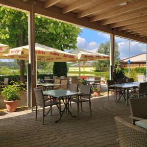 un patio al aire libre con mesas, sillas y sombrillas en Gasthaus Pension Rezatgrund, en Windsbach