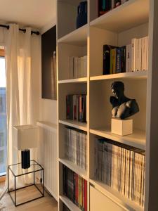 un estante de libros con libros y una estatua en él en Magnifique appartement Paris, bord du canal, en Pantin
