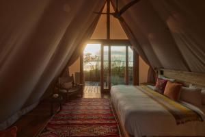 a bedroom with a bed and a large window at Our Habitas Bacalar in Bacalar