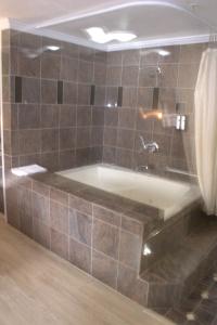 Discovery Inn في هايوارد: حوض استحمام في حمام مع جدار من البلاط