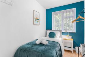 a bedroom with a bed with a blue accent wall at Comfort Zone in Yiewsley