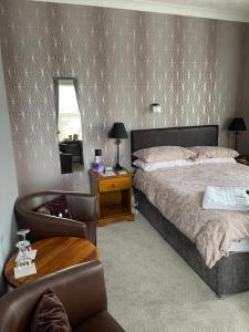 1 dormitorio con cama, silla y espejo en Doriam Guest House en Bridlington