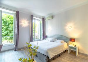 a bedroom with a bed and two windows at Hotel Les Palmiers in Sainte-Maxime
