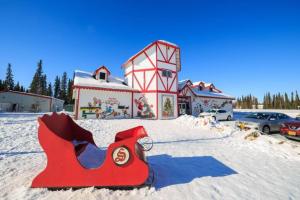 a red santa claus sled in the snow next to a building at The Cub Cottage in North Pole AK in North Pole