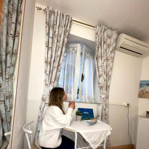 una mujer sentada en una mesa frente a una ventana en Affittacamere Guesthouse Maristella, en Cagliari