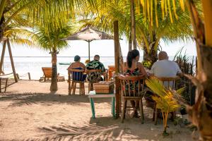 Pousada Enero في ماراغوغي: مجموعة من الناس يجلسون على طاولة على الشاطئ