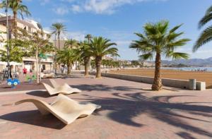 zwei weiße Stühle auf einem Bürgersteig neben einem Strand in der Unterkunft Casa de la musica in Camposol
